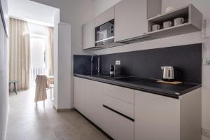 a kitchen with white cabinets and a black counter top at Palazzo Amalfitania in Syracuse