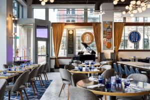 a restaurant with tables and chairs and a piano at BLU-Tique, Akron, a Tribute Portfolio Hotel in Akron