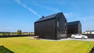 a black house with a car parked in a yard at Modern Villa By The Sea in Palanga