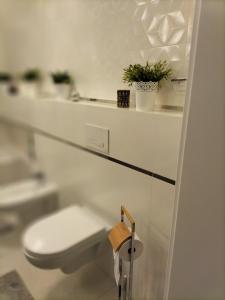 biała łazienka z toaletą i umywalką w obiekcie Kwatera Paprotka 23 w Warszawie