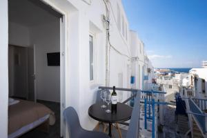 a balcony with a table and a bottle of wine at My White Studio Mykono Town in Mýkonos City