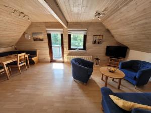 een woonkamer met blauwe stoelen en een tv en een tafel bij Silbersee90 in Frielendorf