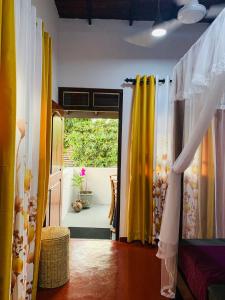 a room with a door open to a patio with yellow curtains at No 31 in Galle