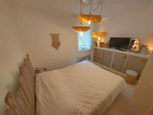 Schlafzimmer mit einem weißen Bett und einem TV in der Unterkunft Le cocon du pêcheur in Trouville-sur-Mer