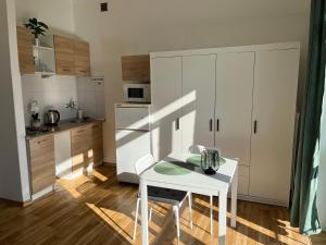 kuchnia z białym stołem i białą szafką w obiekcie Słoneczny apartament na Żoliborzu dla 2 osób przy Arkadii w Warszawie