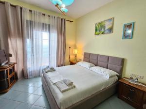 ein Schlafzimmer mit einem Bett und einem großen Fenster in der Unterkunft Villa Meminaj in Vlorë