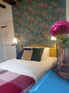 Maison de charme : Ti Pauline. في دينان: غرفة نوم مع سرير مع إناء من الزهور