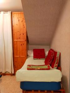Habitación pequeña con cama con almohadas rojas en Le gîte du colombier, en Les Vans