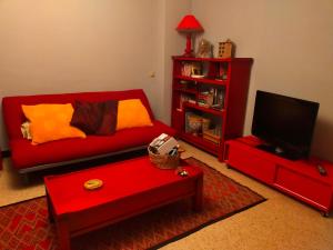 sala de estar con sofá rojo y TV en Le gîte du colombier, en Les Vans