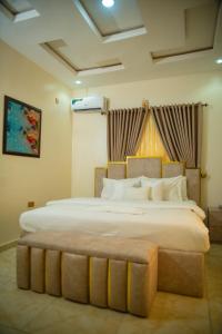 1 dormitorio con 1 cama grande con almohadas blancas en Ennys Court, en Akure