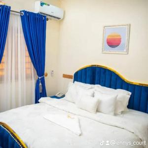 a bedroom with a blue and white bed with white pillows at Ennys Court in Akure