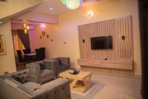 a living room with two chairs and a television at Ennys Court in Akure