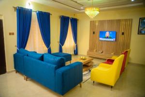 salon z niebieską kanapą i żółtymi krzesłami w obiekcie Ennys Court w Akure