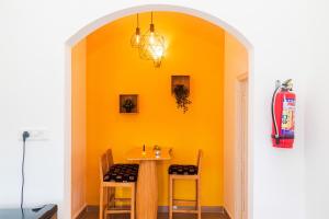a dining room with an orange wall and a table and chairs at Cosmos Inn in Goa