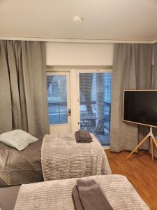 a bedroom with two beds and a flat screen tv at Viihtyisä täysin kalustettu ja varustettu yksiö Logomolla 1vrk-36kk in Turku