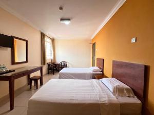 a hotel room with two beds and a desk at Tropicana Hotel in Gemas