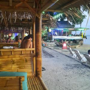 a man sitting at a bar on the beach at Two Rocks Bungalows in Ban Tai
