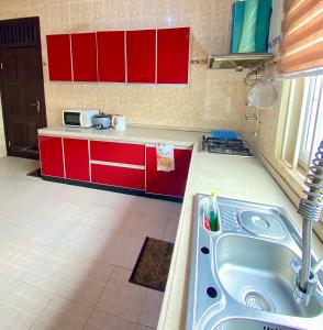 a kitchen with a sink and red cabinets at Bays Villa in Koforidua