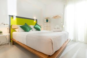 een slaapkamer met een groot wit bed met groene accenten bij KIMIA Guest House in Skiathos-stad