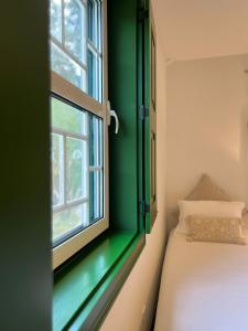 1 dormitorio con pared verde, cama y ventana en Quinta Catrinandes - Retreat Center, en Tondela