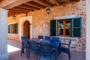 un patio con mesa, sillas y pared de piedra. en Sa Rota de Can Lluch Dimoni, en Lloret de Vistalegre