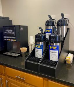 a counter with four bottles of water on a shelf at Bangor Suites Airport Hotel in Bangor