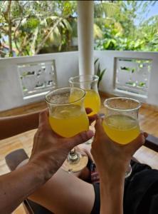 two people holding up two glasses of orange juice at Malika Homestay in Midigama