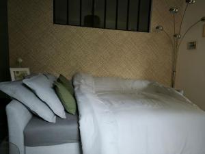 a bed with white sheets and pillows in a room at L'entre-deux in Périgueux