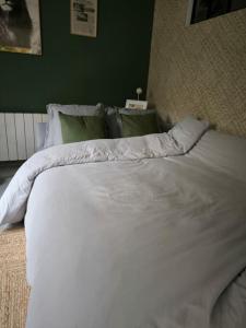 a white bed in a bedroom with a green wall at L'entre-deux in Périgueux