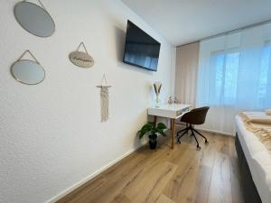 een slaapkamer met een bureau en een tv aan de muur bij 3 Zimmer Apartment, 90 qm, ruhig und zentrumsnah, max 6 Pers, 15 qm Balkon , private Garage, Internet 1000 MBit in Sindelfingen