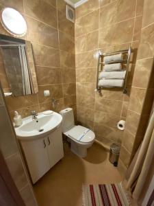 a bathroom with a white toilet and a sink at Hotel Three Korony in Skhidnitsa