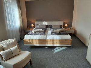 a bedroom with a large bed and a chair at Ferienwohnung am Kapellenberg - am Rande des Nationalparks Schwarzwald in Bad Peterstal-Griesbach