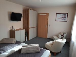 a bedroom with a bed and a chair and a television at Ferienwohnung am Kapellenberg - am Rande des Nationalparks Schwarzwald in Bad Peterstal-Griesbach