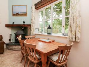 comedor con mesa de madera y chimenea en Pheasants Roost With Indoor Pool In Devon en Broadwoodkelly