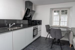 cocina con armarios blancos, mesa y sillas en Kirchweg 22 8750 Glarus en Glarus