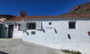 un edificio blanco con un cartel en el costado en Casa Rural LOS PINARES El Juncal de TEJEDA en Tejeda