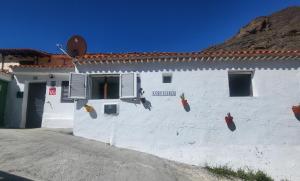 a white building with a sign on the side of it at Casa Rural LOS PINARES El Juncal de TEJEDA in Tejeda