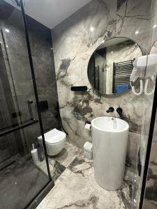 a bathroom with a sink and a toilet and a mirror at LEOGRAND Apartments on Virmenska 14 in Lviv