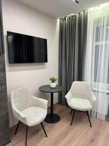 a room with two chairs and a table and a tv at LEOGRAND Apartments on Virmenska 14 in Lviv