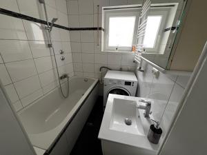 y baño con lavabo, bañera y lavadora. en Best Apartment Augsburg, en Augsburg