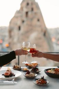 two people holding glasses of wine on a table with food at Carus Cappadocia in Göreme