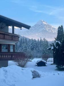 a house in the snow with a mountain in the background at Apartments im Jagdhof in Fischen