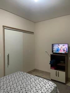 a bedroom with a bed and a flat screen tv at Apartamento próximo ao centro in Primavera do Leste