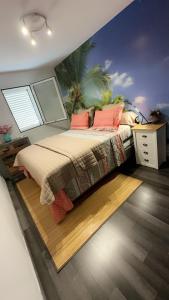 sypialnia z łóżkiem, biurkiem i malowidłem palmowym w obiekcie Appart'Eden : vue panoramique sur Saint-Denis w mieście Sainte-Clotilde