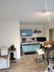 une cuisine avec des armoires bleues, une table et des chaises dans l'établissement Apart Bellagast, à Hilchenbach