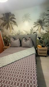 a bedroom with a bed with palm trees on the wall at Appart'Eden : vue panoramique sur Saint-Denis in Sainte-Clotilde
