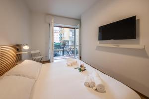 una camera da letto con letto, asciugamani e TV a schermo piatto di CASA SIMONA Comfort moderno in ottima posizione a Rapallo