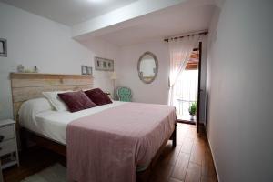 1 dormitorio con cama, espejo y ventana en Casa Rural El Sobraillo, en Villanueva de la Vera