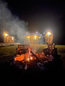 a fire in front of two lodges at night at Matesevo guest houses in Kolašin