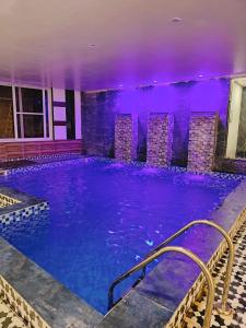 einen großen Pool mit lilafarbener Beleuchtung in der Unterkunft Hotel DC Hills Rishikesh in Rishikesh